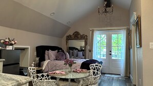 A spacious loft bedroom with a large bed, a chandelier, and a view of the outdoors. - Saint Jo Wine Country Loft Near Blue Ostrich Winery (Saint Jo)