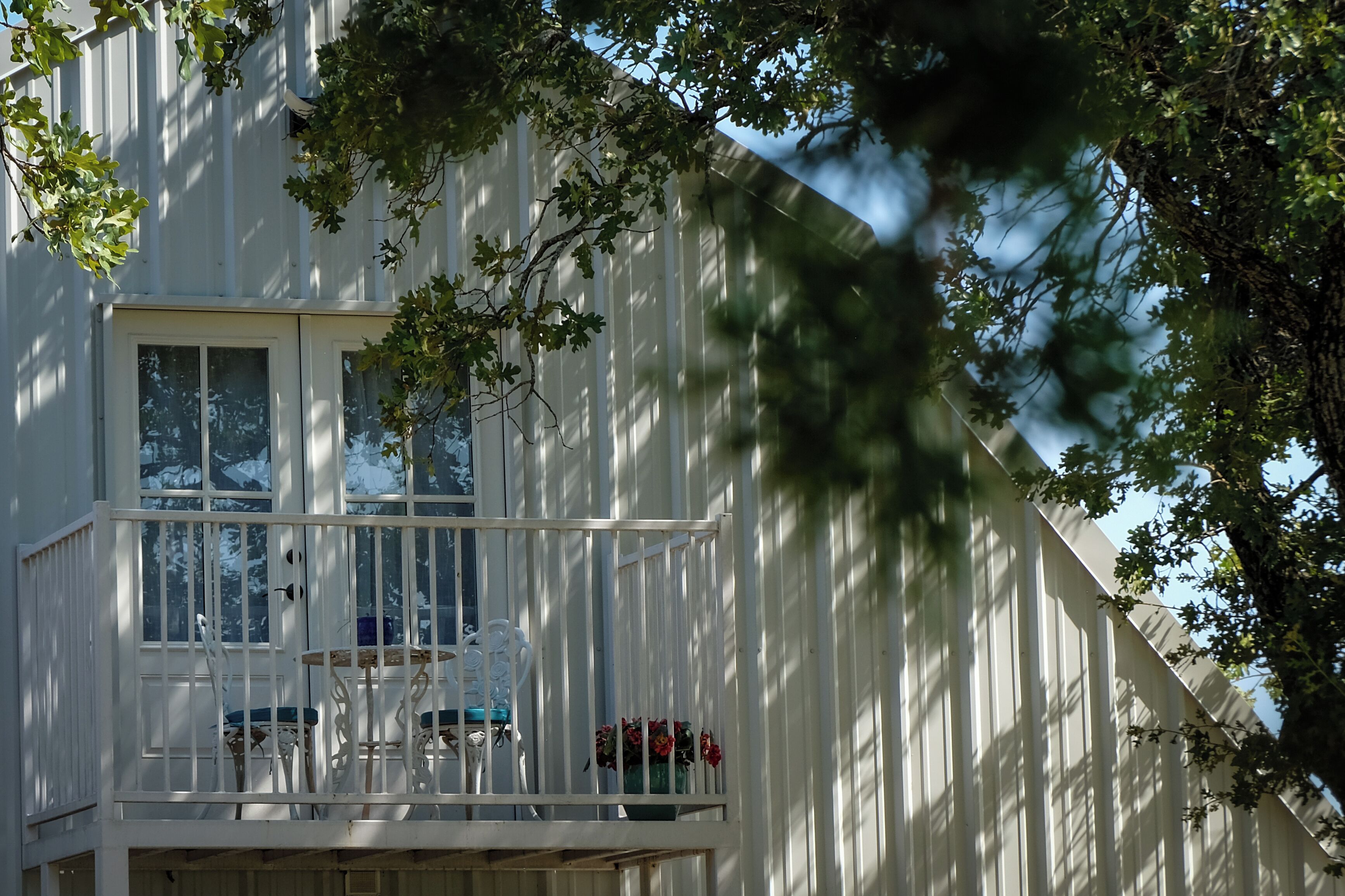 A white building with a balcony, a window, and a door.