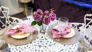 A round glass table with a white lace doily centerpiece, two white chairs, and a vase with pink flowers. - Saint Jo Wine Country Loft Near Blue Ostrich Winery (Saint Jo)