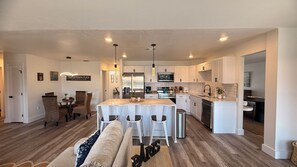 A modern kitchen with white cabinetry, stainless steel appliances, and a central island with bar stools. - Waterfront home with pool, billiards, 4 min beach (Punta Gorda)