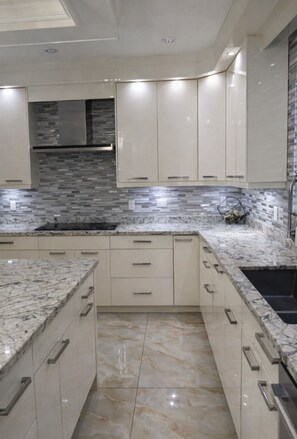 A modern kitchen with marble countertops, beige cabinetry, and a tiled backsplash. - Spacious 5BR North Delta Retreat, Near Shops, Hwy & Parking (Delta)