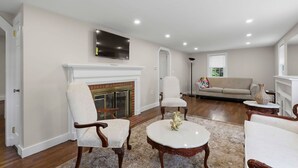 Una sala de estar con chimenea, televisor montado sobre ella, sofá y una mesa de centro.