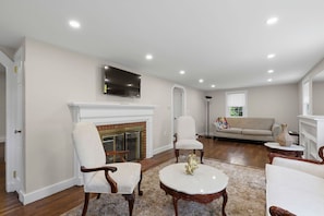 A living room with a fireplace, a television mounted above it, a sofa, and a coffee table. - NEW Listing Walk to Main Street and Hyannis Harbor (Barnstable)