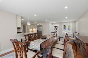 A dining room with a long table, wooden chairs, and a floral tablecloth. - NEW Listing Walk to Main Street and Hyannis Harbor (Barnstable)