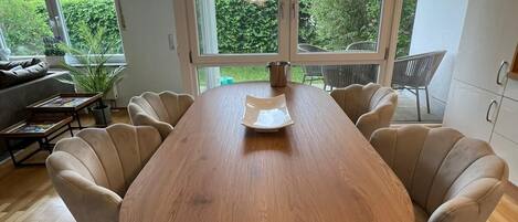 Un comedor moderno con una mesa de madera, seis sillas y grandes ventanales con vistas a la vegetación.