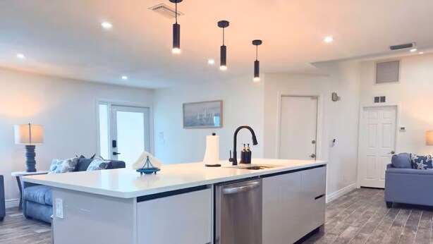 A modern kitchen with a central island, built-in dishwasher, and pendant lighting. - Casa Azul/Tropical Paradise/Heated Pool/Private (Cape Coral)