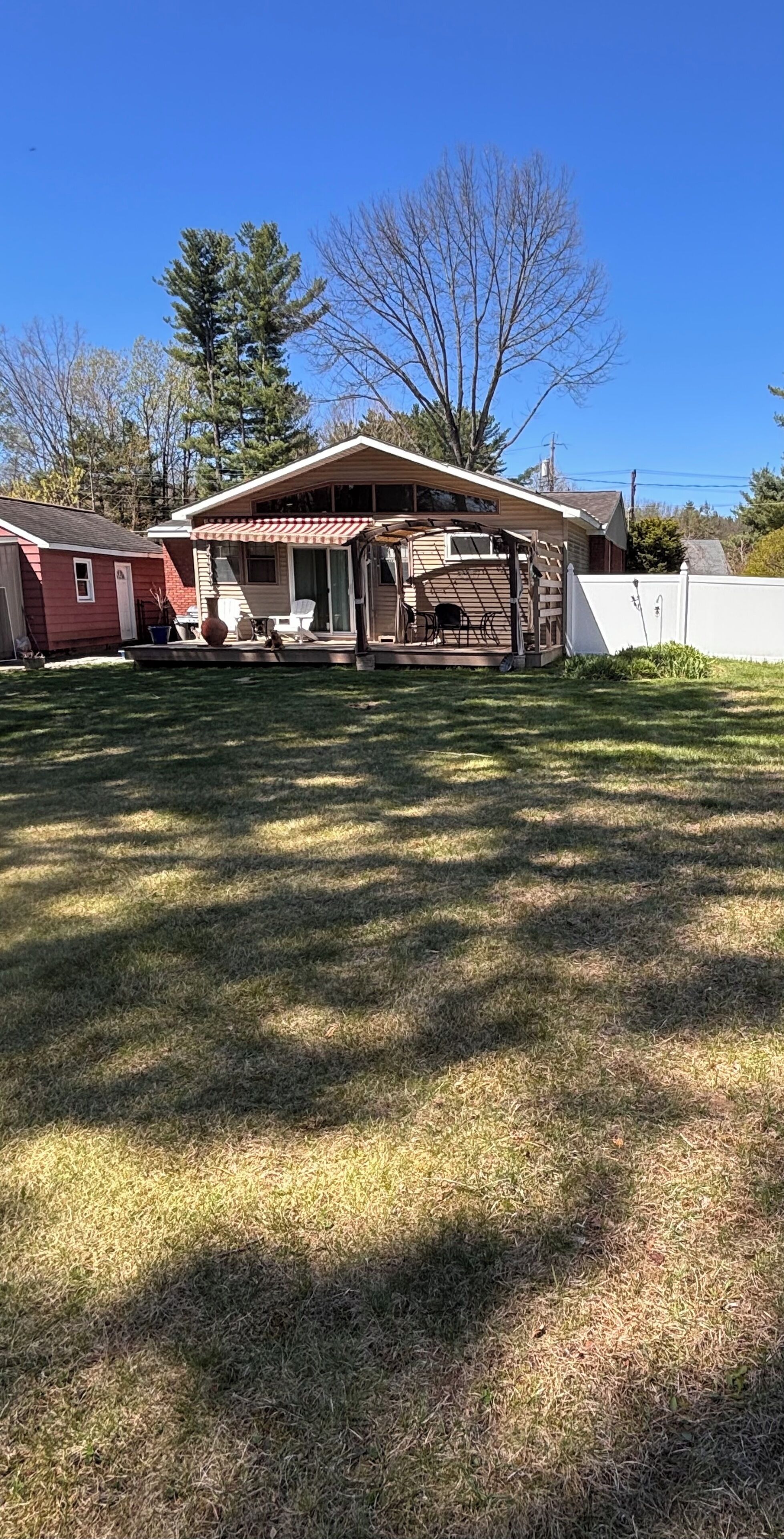 A residential property with a covered patio, a red shed, and a white fence.