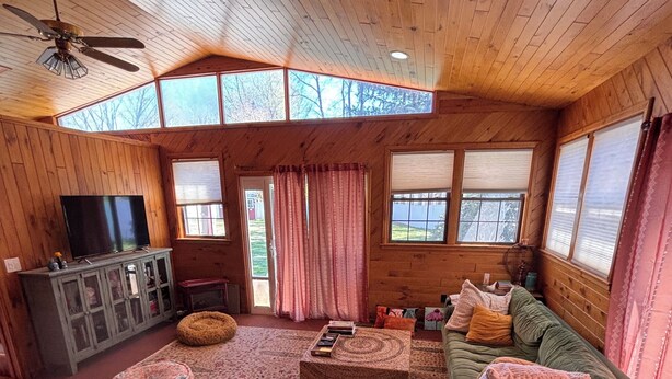 A cozy cabin interior with a wooden ceiling, a television on a cabinet, a sofa, and a patterned rug. - Beautiful, Family friendly home in Saratoga Springs, NY. 2.2 Miles from track, (Saratoga Springs)