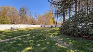 A grassy backyard with a white fence, a shed, and a small wooden structure. - Beautiful, Family friendly home in Saratoga Springs, NY. 2.2 Miles from track, (Saratoga Springs)