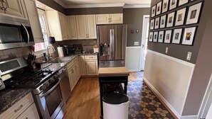 A kitchen with stainless steel appliances, wooden cabinets, and a patterned floor. - Beautiful, Family friendly home in Saratoga Springs, NY. 2.2 Miles from track, (Saratoga Springs)