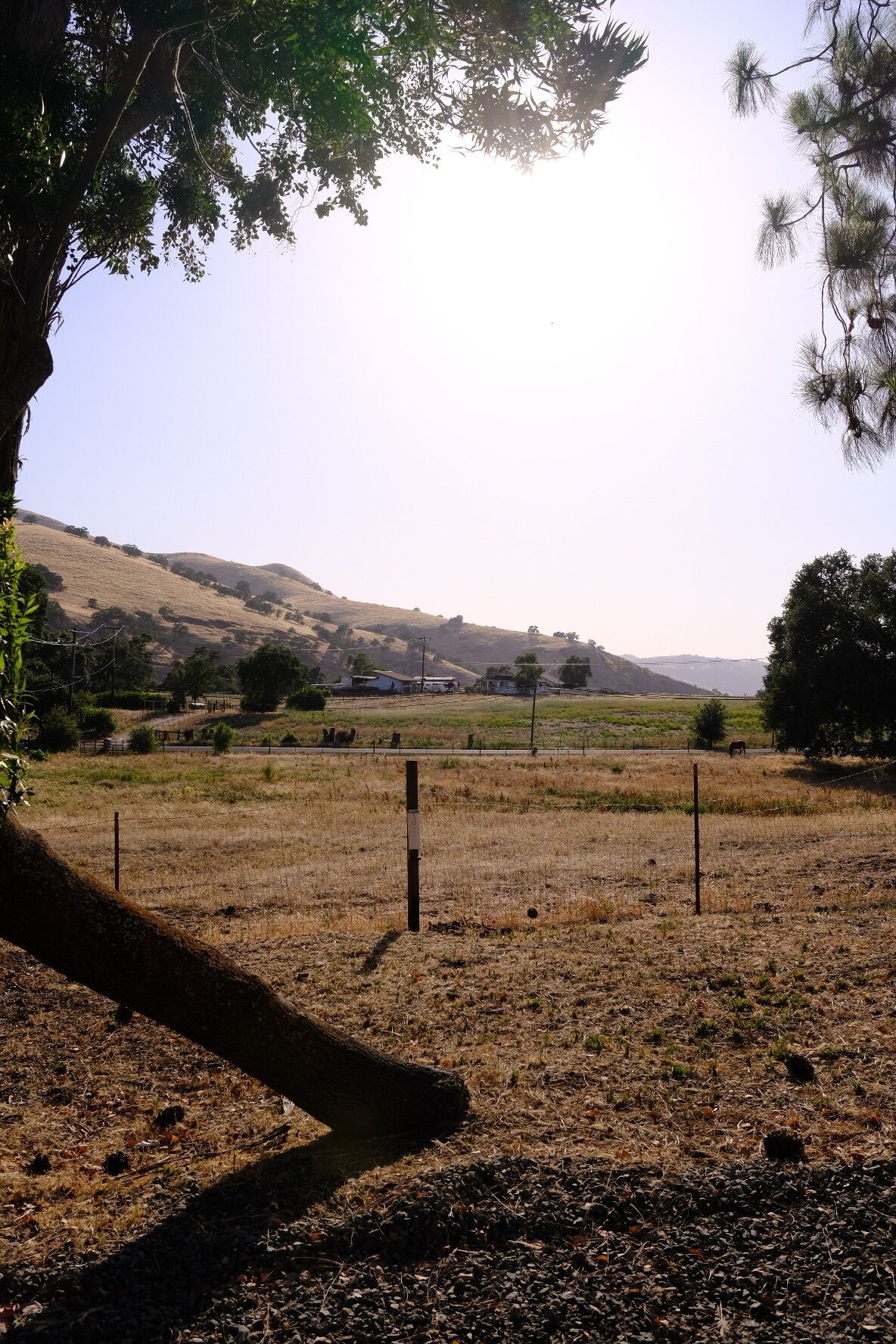 A rural landscape with a field, a fence, and distant hills.