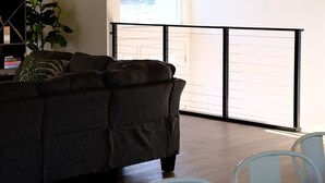 Ein modernes Wohnzimmer mit Holzboden, einer Couch, einem Esstisch und Blick durch eine Glastür.