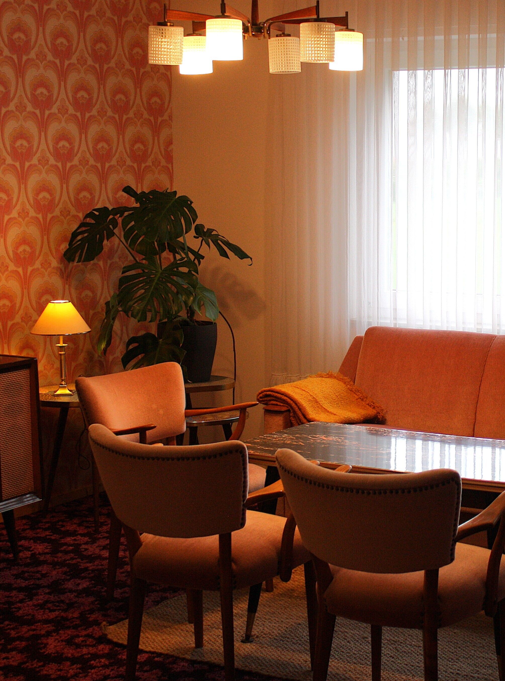 A dining area with a table, chairs, a potted plant, a lamp, and a sofa.
