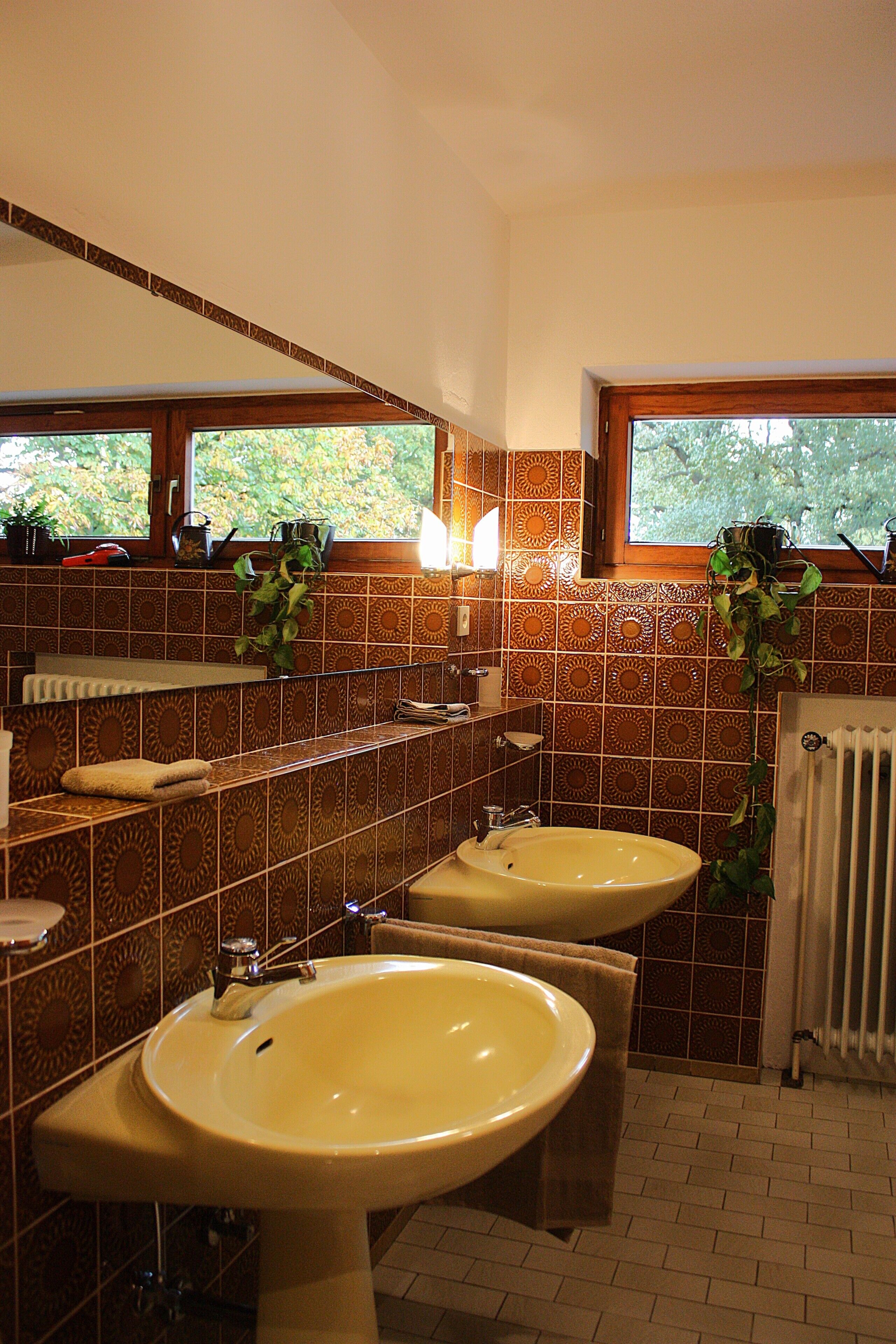 A bathroom with two sinks, a window, and patterned tiles.