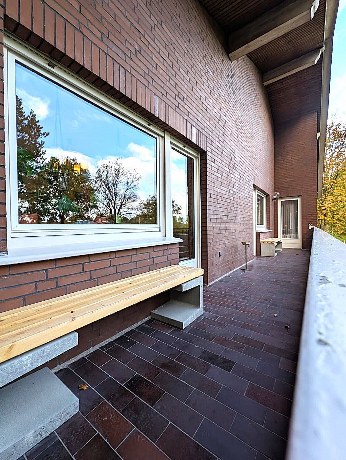 A modern building with large windows, a wooden bench, and a brick exterior.