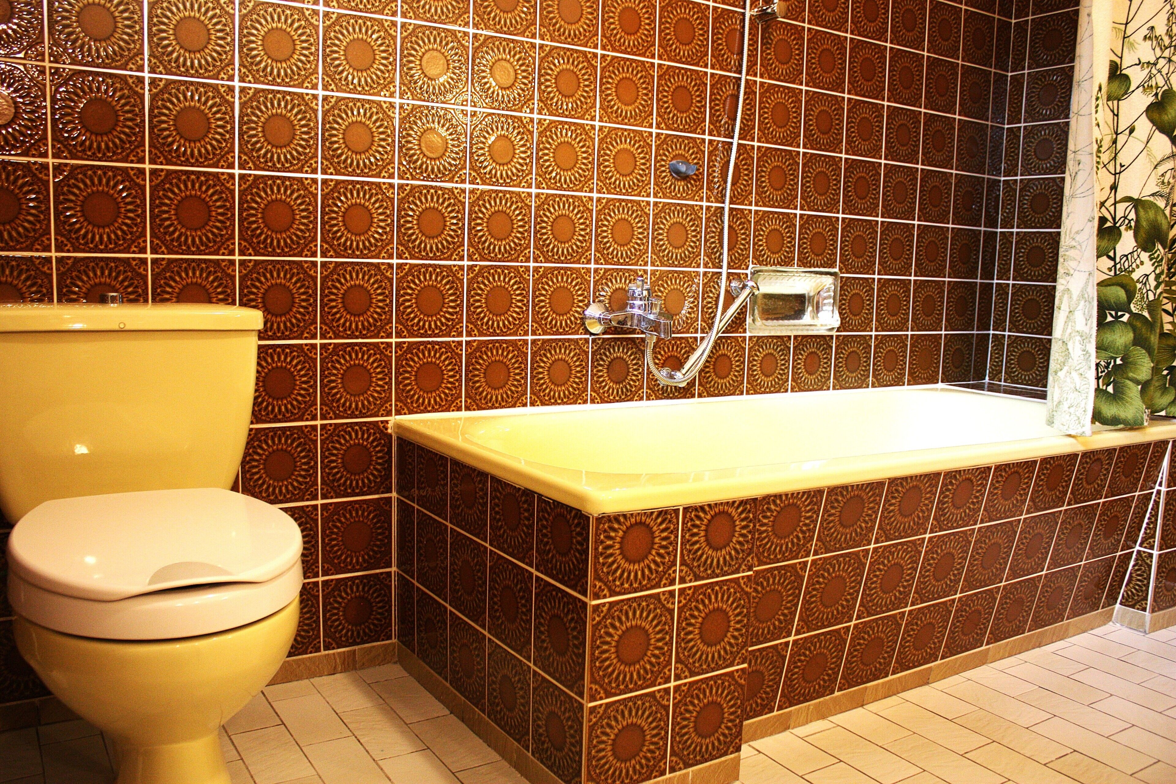 Une salle de bain avec des toilettes, une baignoire et des carreaux décoratifs sur les murs.