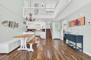 A spacious kitchen with a wooden bench, a staircase, and a dining area. - Blue Heaven 2.0 by Brunswick Vacation Rentals:  2nd Row Beach Retreat with Pool (Ocean Isle Beach)