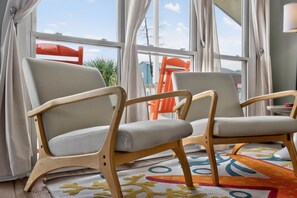 Two wooden chairs with fabric seats and backs, a colorful rug, and a window with curtains. - Crow's Nest by Brunswick Vacation Rentals: 4BR Pool Home Walk to Beach Sleeps 12 (Ocean Isle Beach)