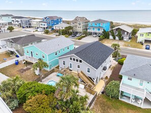 A coastal residential area with houses, a swimming pool, and a view of the ocean. - Crow's Nest by Brunswick Vacation Rentals: 4BR Pool Home Walk to Beach Sleeps 12 (Ocean Isle Beach)