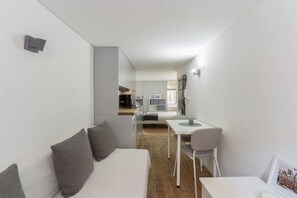 Ein gemütlicher Wohnbereich mit einer Couch, einem Esstisch und einer kleinen Küchenzeile im Hintergrund.