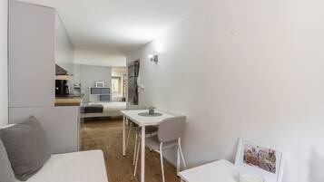 Een ruimtelijk ingerichte woonruimte met kitchenette, een eethoek en een zithoek.