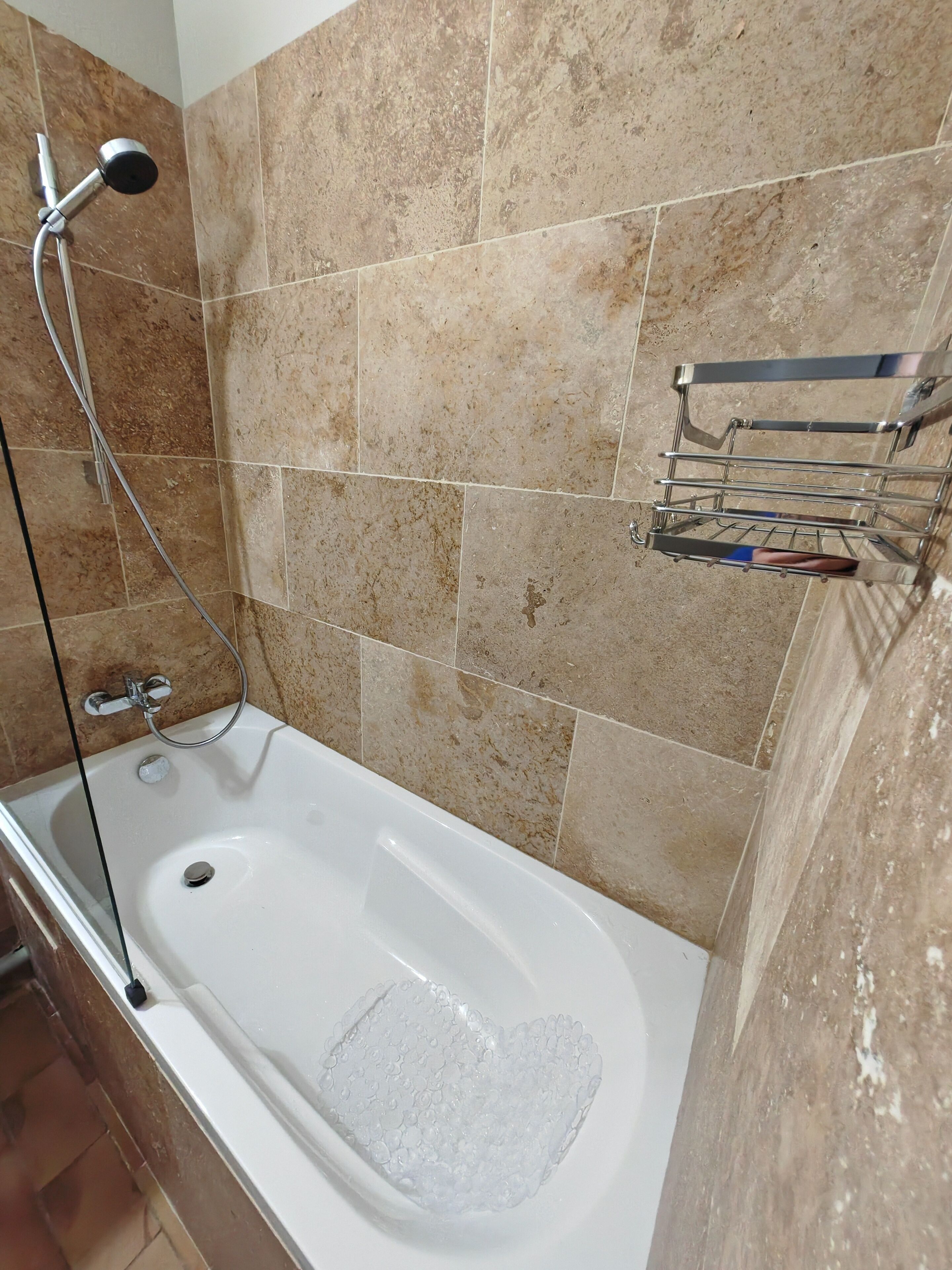A bathroom with a bathtub, a shower head, and a towel rack.
