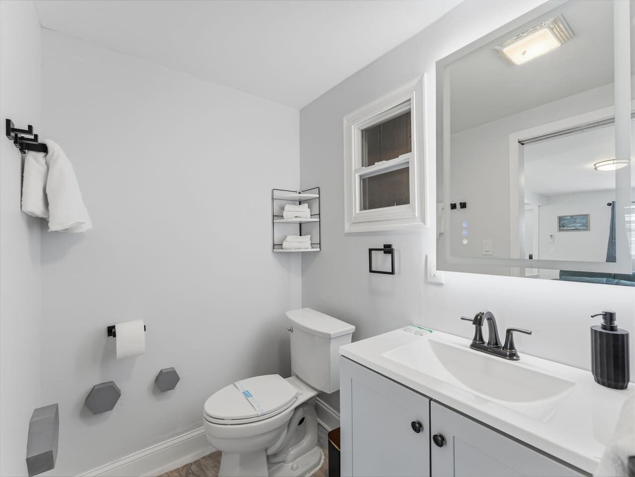 Un baño moderno con inodoro, lavamanos, espejo y toallero.
