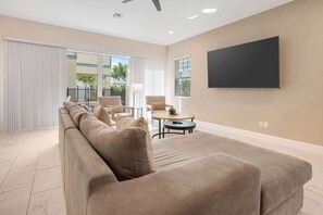 Ein modernes Wohnzimmer mit einem großen Sofa, einem Couchtisch und einem flachbildfernseher, der an der Wand montiert ist.
