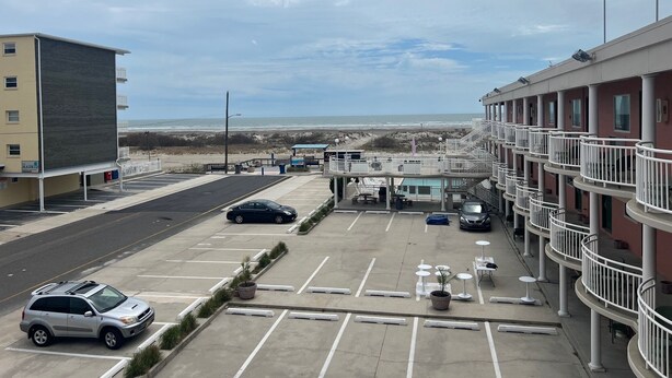 A parking lot with a building in the background, a beach view, and a pool area. - OCEANFRONT PENTHOUSE (Wildwood Crest)