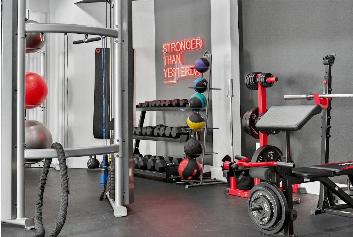 A gym with weightlifting equipment, a bench press, and a motivational sign.