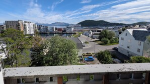 Et boligområde med moderne bygninger, en havnefront og et bjerg i baggrunden.