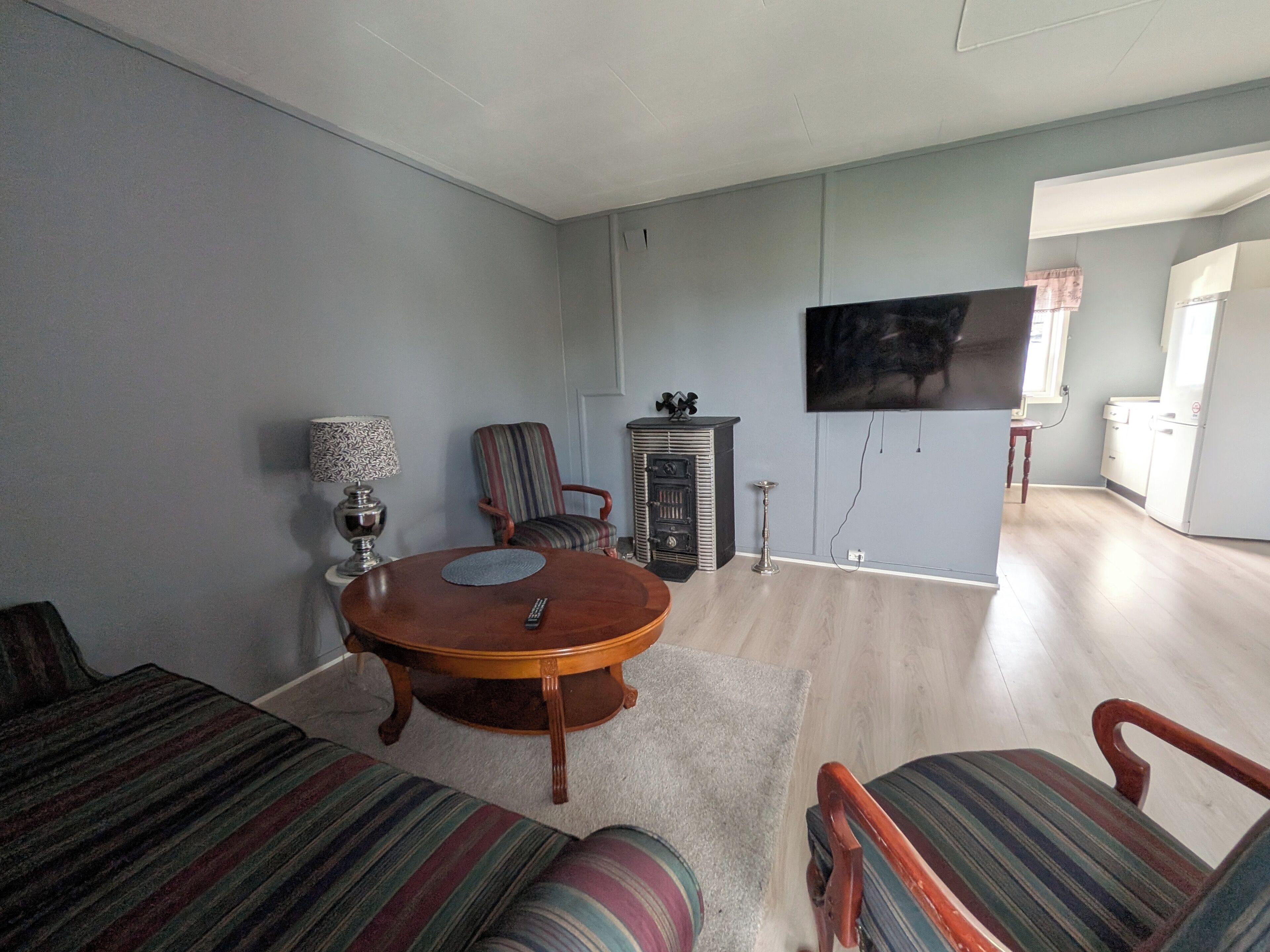 Ein Wohnzimmer mit einem runden Holztisch, gestreiften Sofas, einem Fernseher und einem Kamin.