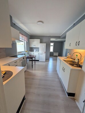 A modern kitchen with white cabinets, a central island, and a built-in oven.