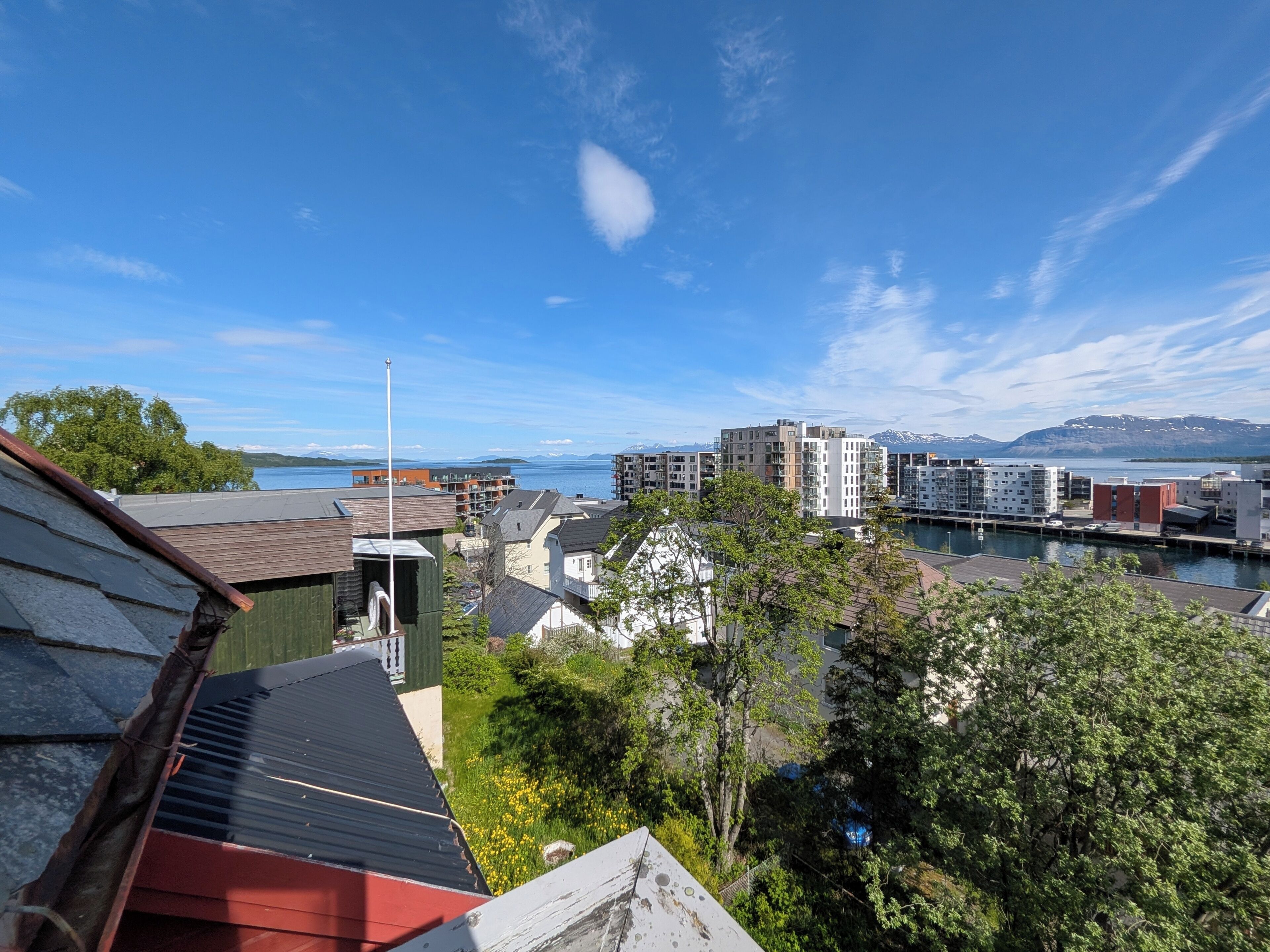 A residential area with modern buildings, a clear sky, and a body of water in the background.