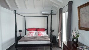 Un lit à baldaquin au revêtement foncé, une petite table de chevet avec une lampe et un tableau encadré au mur.