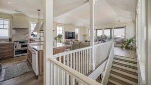 A spacious kitchen with modern appliances, a dining area with a large island, and a living room with a view. - Private pool, putting green, kayaks, beautiful sunsets, ocean & marsh views! (Fripp Island)