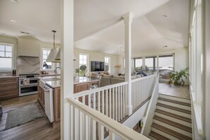 A spacious kitchen with modern appliances, a dining area with a large island, and a living room with a view. - Private pool, putting green, kayaks, beautiful sunsets, ocean & marsh views! (Fripp Island)