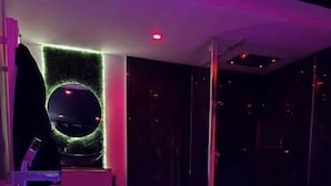 Un interior moderno con zona de piscina, una fuente circular y una pared iluminada con neón.