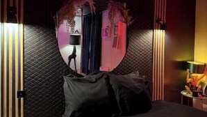 Un dormitorio moderno con un espejo grande, una cama y una mesita de noche con lámpara.