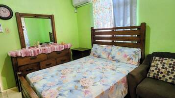 A bedroom with a bed, a dresser, a mirror, and a sofa.