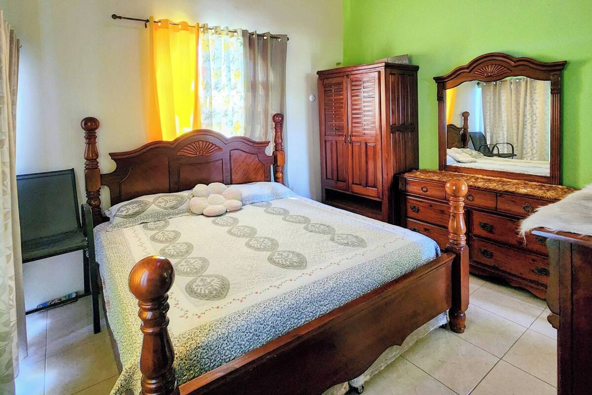 Une chambre à coucher avec un lit en bois, une armoire, un miroir et un téléviseur.