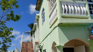 A multi-story building with a staircase leading to a balcony, a door, and a window with decorative bars.