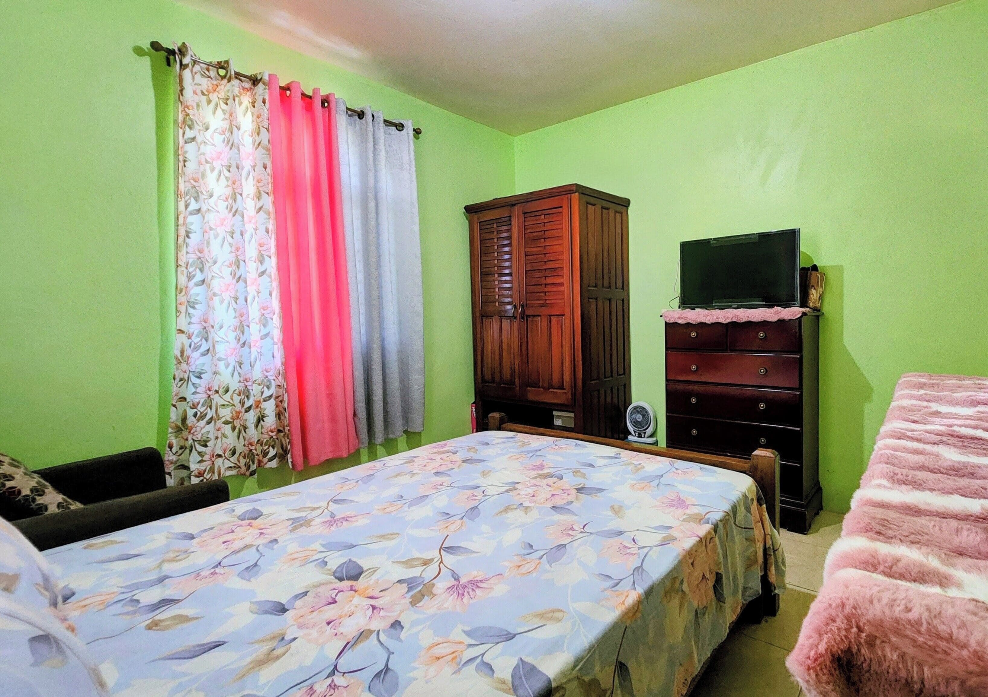 A bedroom with a bed, a dresser, a television, and a wardrobe.