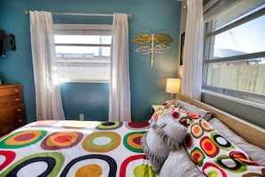 A bedroom with a bed, a dresser, a window with curtains, and a wall decoration. - Retro Sarasota Haven: Private Yard| BBQ |Downtown (Sarasota)