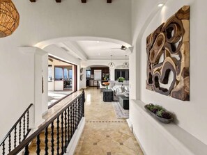 A spacious hallway with a staircase, a dining area, and a kitchen in the background.