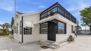 A single-story building with a black front door, white walls, and a small porch area. - Clearwater charm 1/1-A (Clearwater)