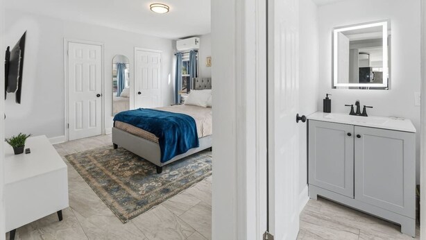 A bedroom with a bed, bedside table, and a bathroom with a sink and mirror. - Clearwater charm 1/1-A (Clearwater)