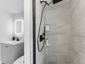 Ein modernes Badezimmer mit Dusche, Waschbecken und Spiegel.