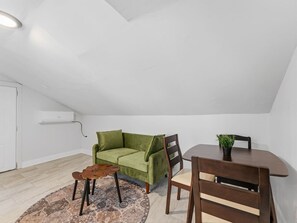 A room with a green sofa, a wooden table, a chair, a small rug, and a ceiling light. - Clearwater charm top unit B (Clearwater)