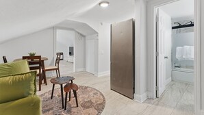 Zona d'estar àmplia amb sostre alçat, menjador, sofà i nevera.